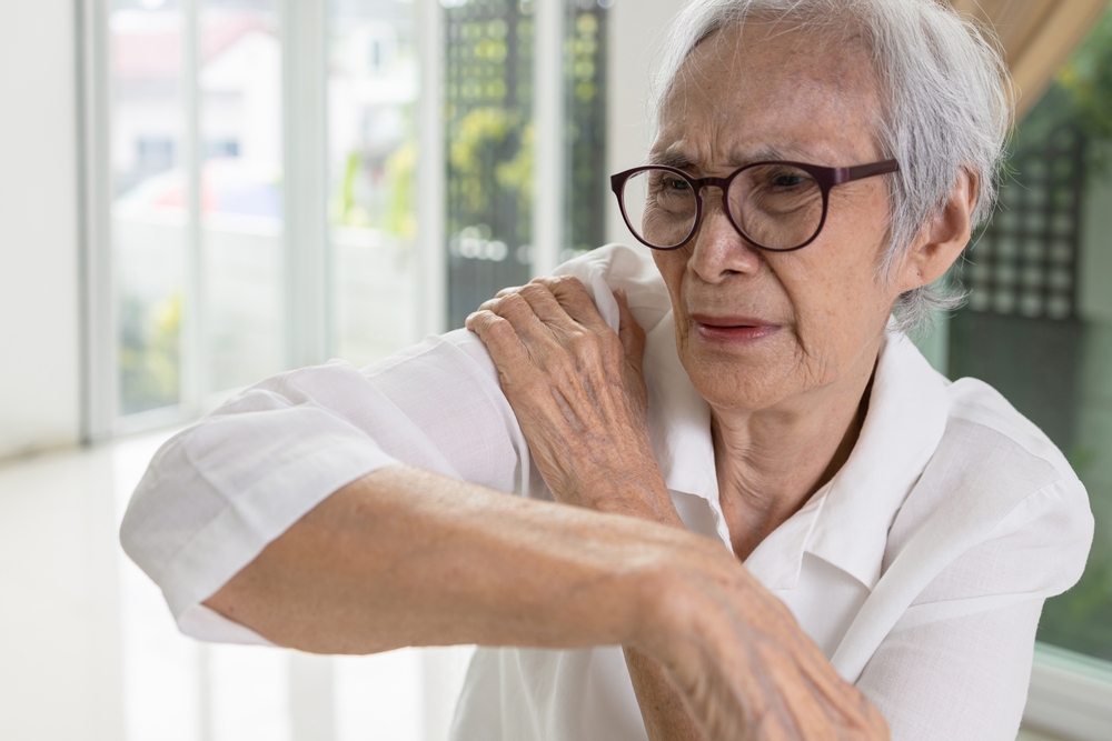 elderly woman massaging her right shoulder